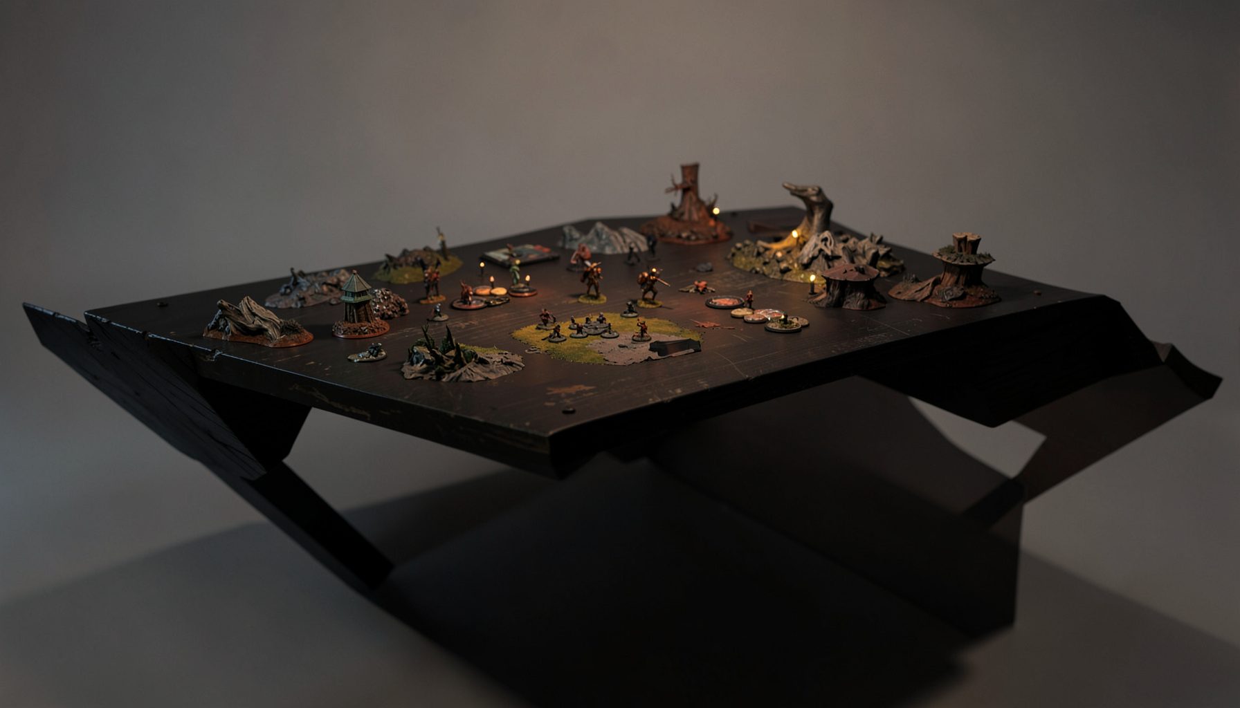 A dark atmospheric tabletop gaming table with terrain pieces and miniatures, lit from above in warm amber tones against a muted olive and charcoal backdrop